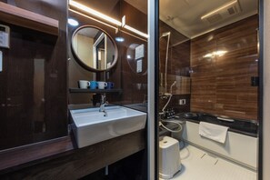 Ein modernes Badezimmer mit großem Spiegel, Waschbecken und Duschbereich.