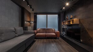 Una sala de estar moderna con un sofá de cuero, un televisor de pantalla plana y piso de madera.