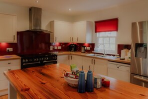 A modern kitchen with a wooden countertop, stainless steel appliances, and a red window blind.