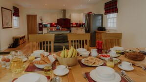A breakfast setting with a table set for four, including plates, bowls, cups, and a variety of breakfast items. - Sherrabeg Cottage -  a cottage that sleeps 8 guests in 4 bedrooms (Laggan)