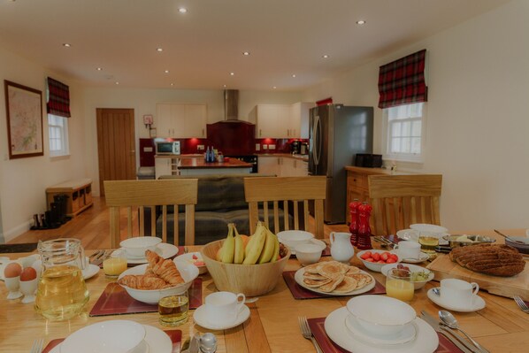 A breakfast setting with a table set for four, including plates, bowls, cups, and a variety of breakfast items.