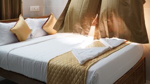 A hotel room with a bed, curtains, a ceiling fan, and an air conditioning unit. - Golden Dawn Residency (Tiruvannamalai)
