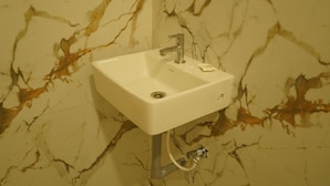 A bathroom sink with a marble backsplash. - Golden Dawn Residency (Tiruvannamalai)