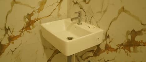 A bathroom sink with a marble backsplash.