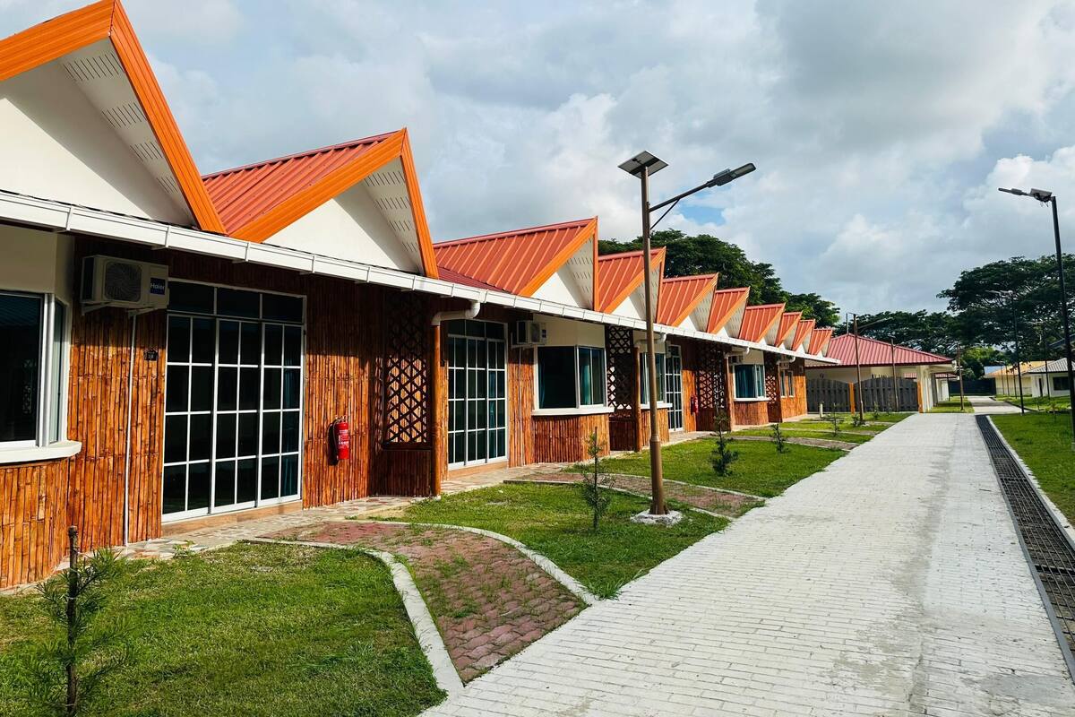 A row of modern hotel rooms with large windows and a red roof.