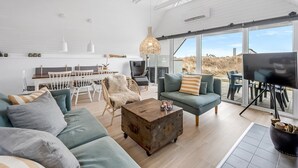 A spacious living area with a high ceiling, large windows, and a cozy seating arrangement.