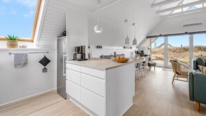 A modern kitchen with a central island, white cabinetry, and a large window.