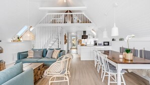 A modern, open-plan living space with a kitchen, dining area, and staircase.