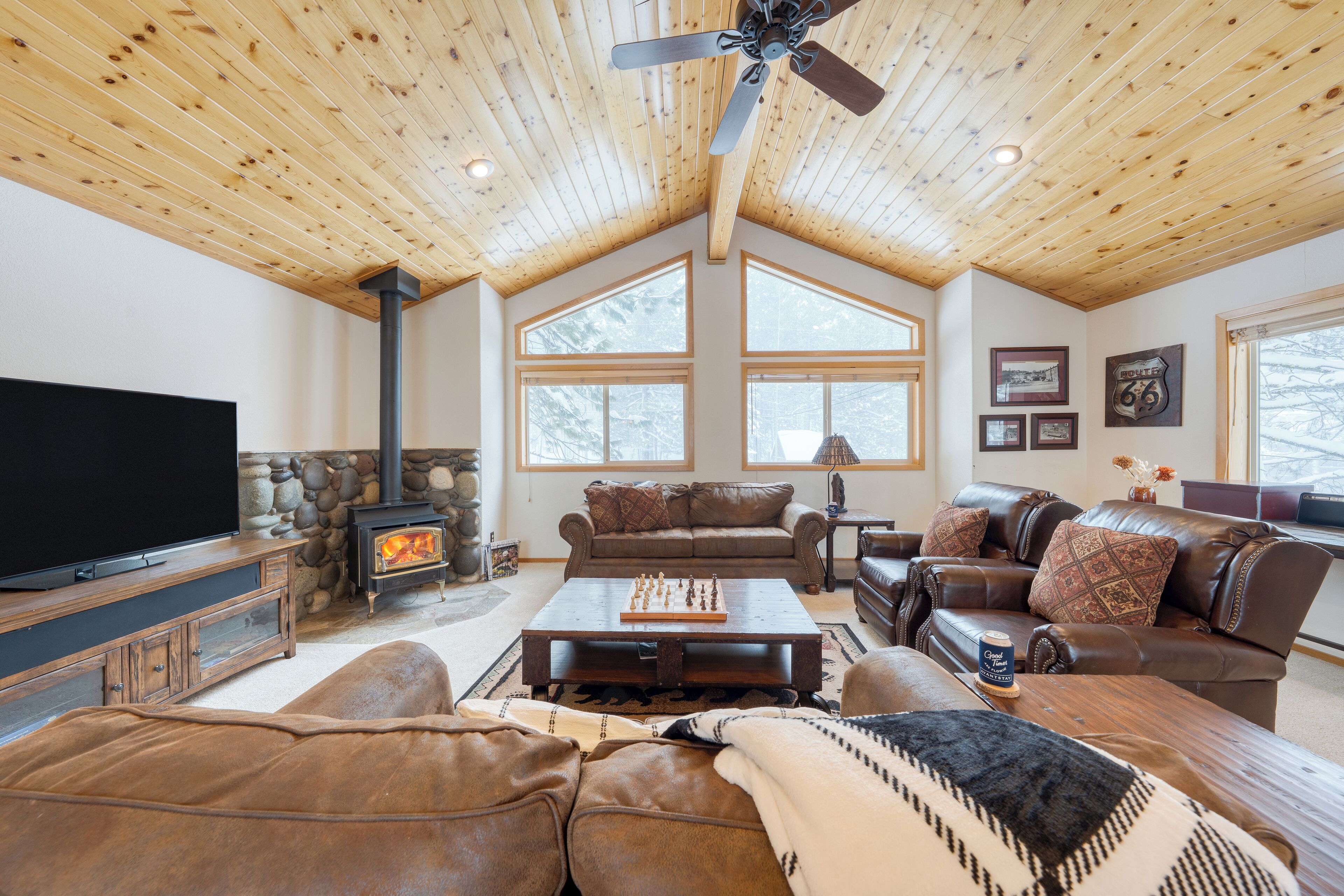 A cozy living room with a fireplace, leather furniture, and large windows.
