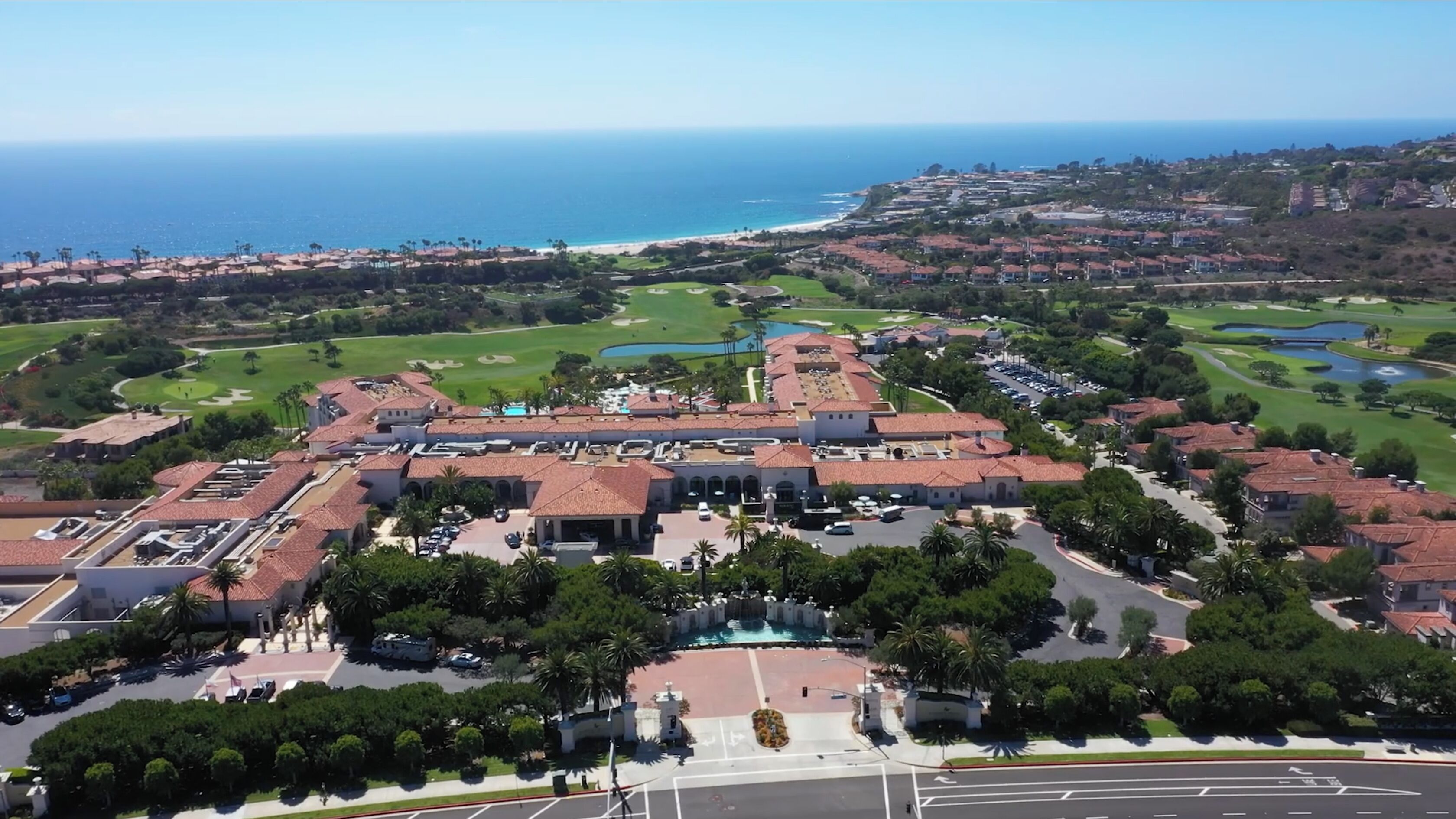 An aerial view of a resort with a large building, a swimming pool, and a golf course.
