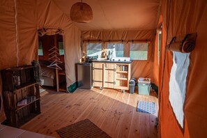 Cozy tented accommodation with a kitchenette area, seating area, and storage options.