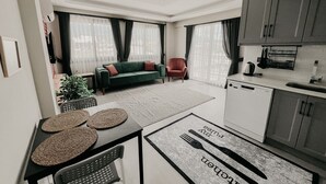 Uma sala de estar moderna com um sofá verde, uma poltrona vermelha e uma área de jantar com mesa e cadeiras.