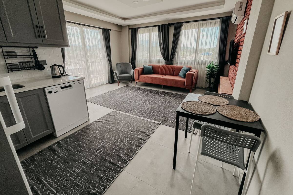Un espacio habitable compacto con kitchenette, un sofá, una mesa de comedor y un televisor.