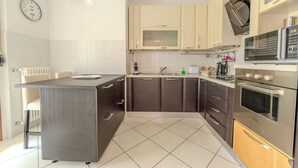 Una cocina moderna con una isla central, electrodomésticos de acero inoxidable y armarios de colores claros.