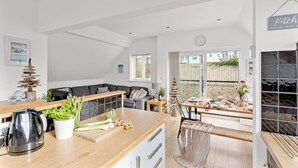 Una cocina moderna con encimera de madera, hervidor y zona de comedor con mesa y sillas.