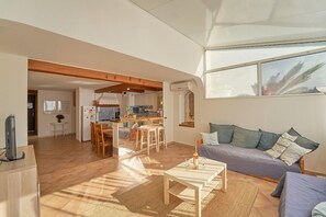 A spacious living area with a sofa, a coffee table, and a kitchen in the background.