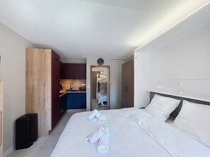 A hotel room with a large bed, a small kitchenette, and a separate bathroom.