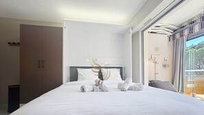 A modern hotel room with a large bed, a wardrobe, and a view of greenery through the window. - Studio Coco`B, 4p, A/C, Wi-Fi, beach 500m, parking (Fréjus)