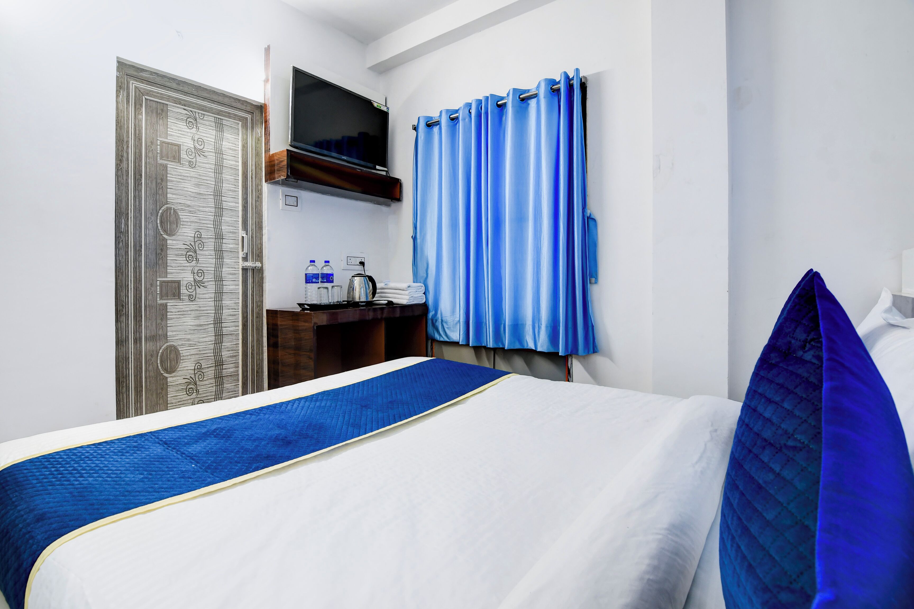 A hotel room with a bed, a desk, a TV, and a bathroom area.