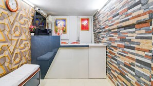 Una habitación moderna con un muro de estampado geométrico, un sofá azul, un mueble blanco y una pared con textura de piedra.