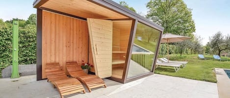 Et moderne udendørs loungeområde med træbænke og en glasindfatning.