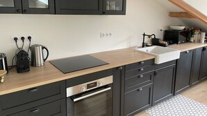 A modern kitchen with dark cabinets, a wooden countertop, a built-in oven, and a sink. - Lovely, warm, fully renovated apartment in the center of the village (Ax-les-Thermes)