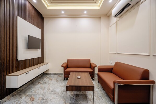 Departamento Deluxe, vista a la ciudad | Área de sala de estar | Televisión LED de 43 pulgadas con canales vía satélite y Netflix 
