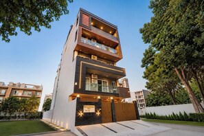 A multi-story building with balconies, a gated entrance, and a well-maintained lawn. - Lime Tree One BHK Service Apartment Gurgaon (Gurugram)