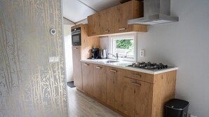 Een moderne keuken met houten kastjes, een gasfornuis en een raam dat voor natuurlijk licht zorgt.