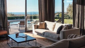 A modern living room with a large glass door leading to a pool, a sofa, and a coffee table. - Villa Misto I, Spacious 5-bedroom villa with panoramic sea views, private pool & game room (Primošten)
