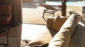 A modern living room with a large window overlooking a pool and outdoor area. - Villa Misto I, Spacious 5-bedroom villa with panoramic sea views, private pool & game room (Primošten)