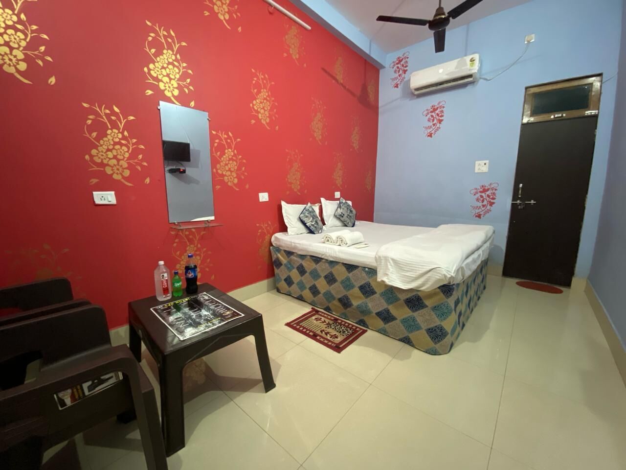 A room with a bed, a small table with items, a mirror, and a door.