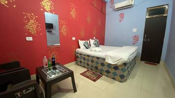 A room with a bed, a small table with items, a mirror, and a door.