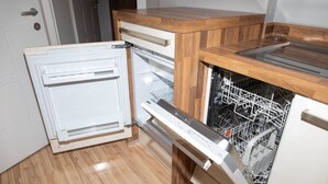 Een keuken met een ingebouwde vaatwasser, houten keukenkastjes en een witte koelkast.