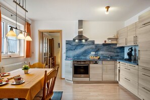 Eine moderne Küche mit Marmorfliesenspiegel, Edelstahlgeräten und Holzschränken.