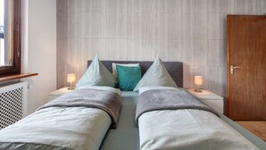 Ein Doppelbett mit zwei Nachttischen, eine Holztür und eine Heizung.