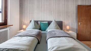 Ein Doppelbett mit zwei Nachttischen, eine Holztür und eine Heizung.