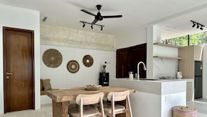 Una cucina moderna con tavolo da pranzo in legno, due sedie, una ventola a soffitto e un'isola integrata con lavello.