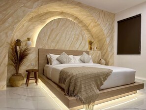 A modern bedroom with a bed, a wooden headboard, a decorative arch, and a vase on the nightstand. - Spring Villa (Nusa Dua)