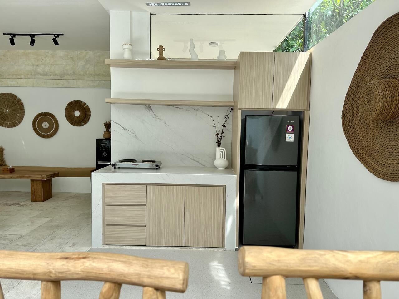 Una cocina moderna con encimera de mármol, armarios de madera, un refrigerador negro y una zona de comedor con bancos.