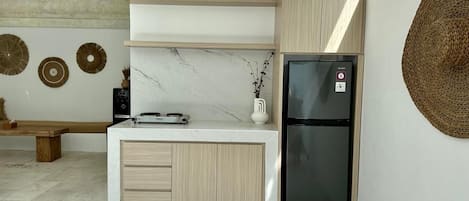 Una cocina moderna con encimera de mármol, armarios de madera, un refrigerador negro y una zona de comedor con bancos.
