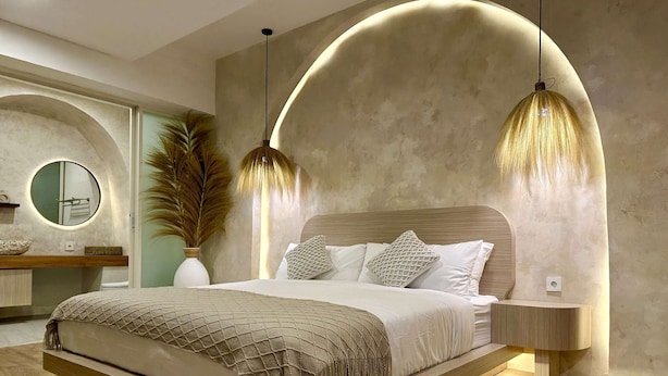 Una camera da letto moderna con un letto grande, due comodini, uno specchio rotondo e una pianta in vaso.