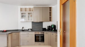 A modern kitchen with built-in appliances, a countertop, and a wooden door.