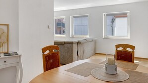 A dining area with a wooden table, chairs, a white cabinet, and a sofa.