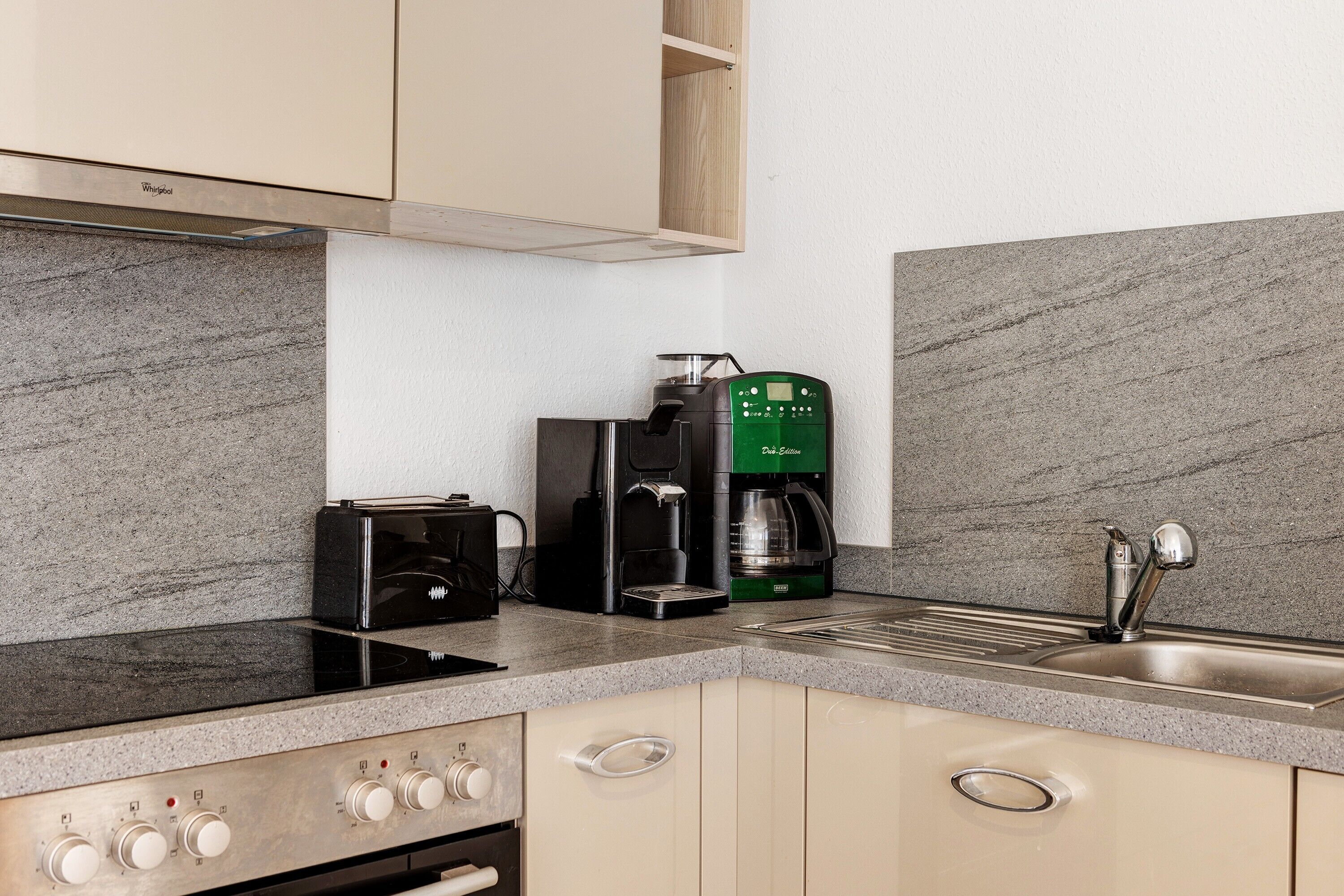 Una cocina con estufa integrada, cafetera y lavaplatos.