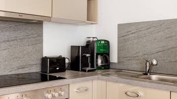 Una cocina con estufa integrada, cafetera y lavaplatos.