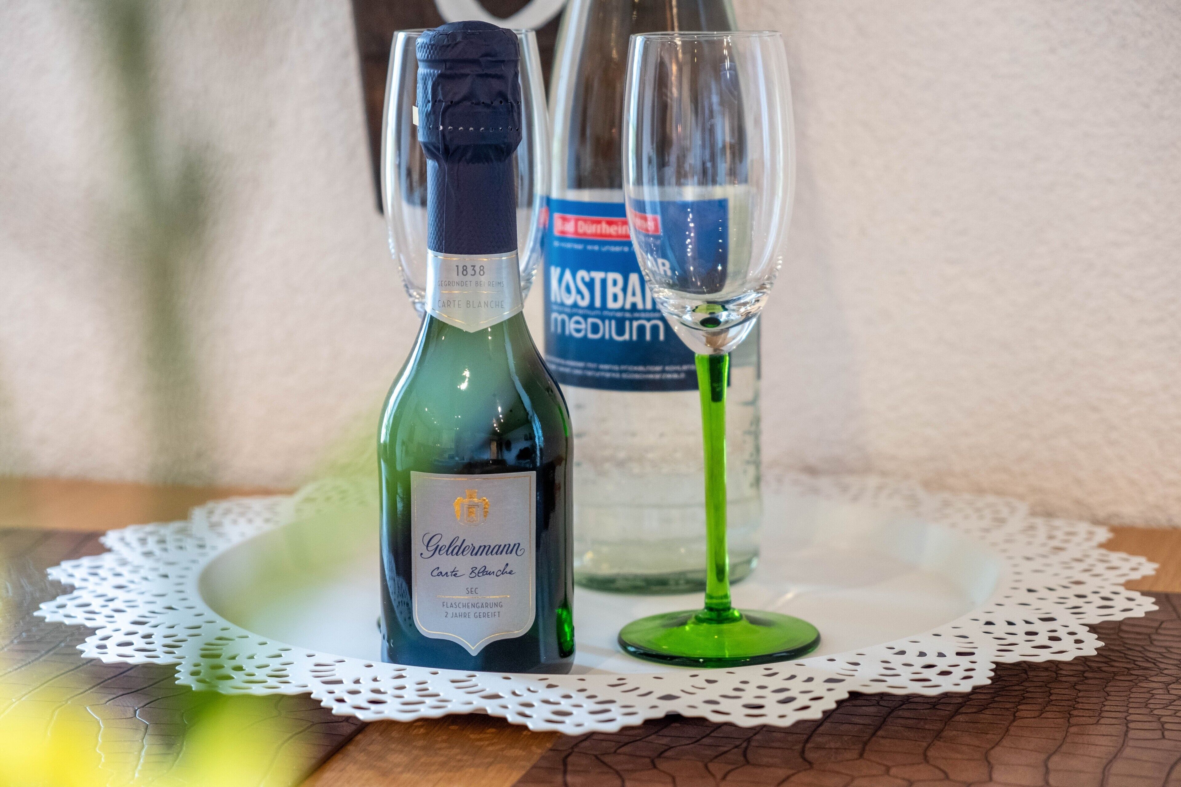 Une bouteille de vin Goldermann et un verre sur une table, avec un chemin de table.