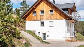 A wooden chalet with a balcony, a paved driveway, and a view of the surrounding forest. - Apartment 'Rudemsmännchen' with Terrace and Garden (Eisenbach (Hochschwarzwald))
