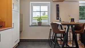 A kitchen with a window, a clock, and a bar area with stools. - Apartment 'Rudemsmännchen' with Terrace and Garden (Eisenbach (Hochschwarzwald))