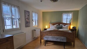 A bedroom with a wooden bed, a bench, a dresser, and two bedside tables with lamps.